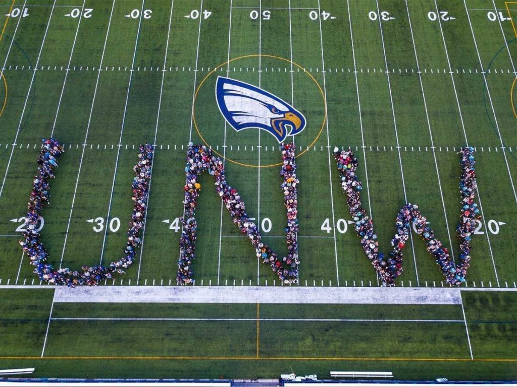 Students on an athletic field. Spelling out UNW