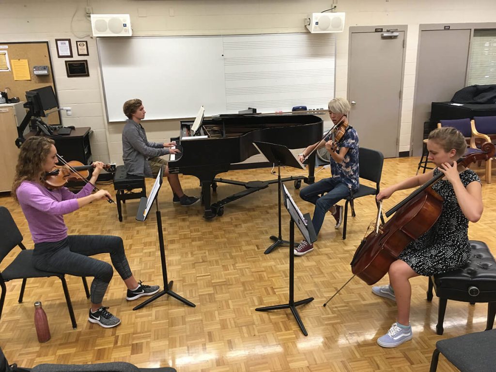 students playing instruments together in a music room