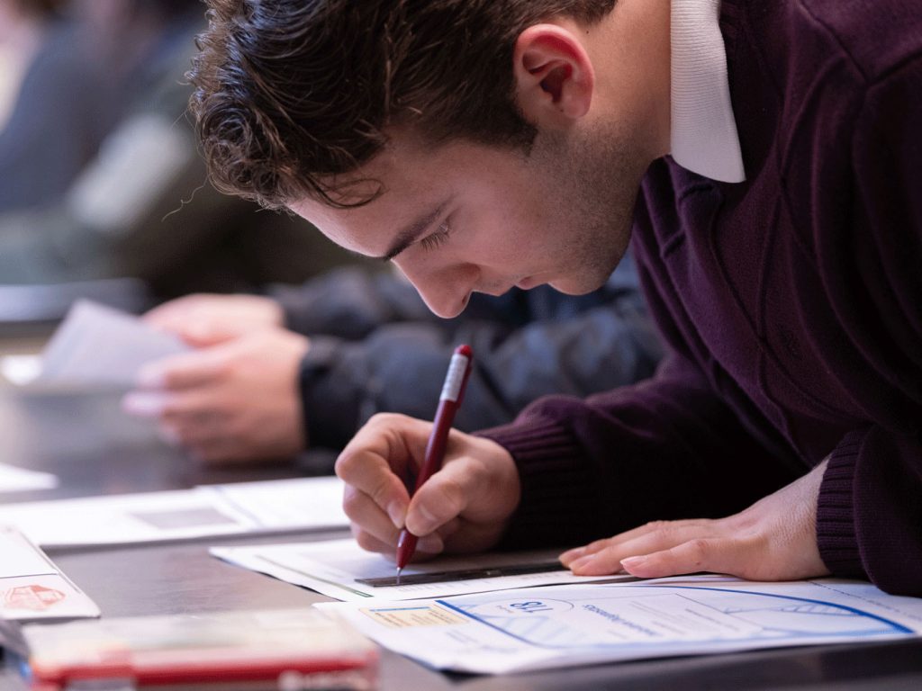 Male student taking notes at his desk.