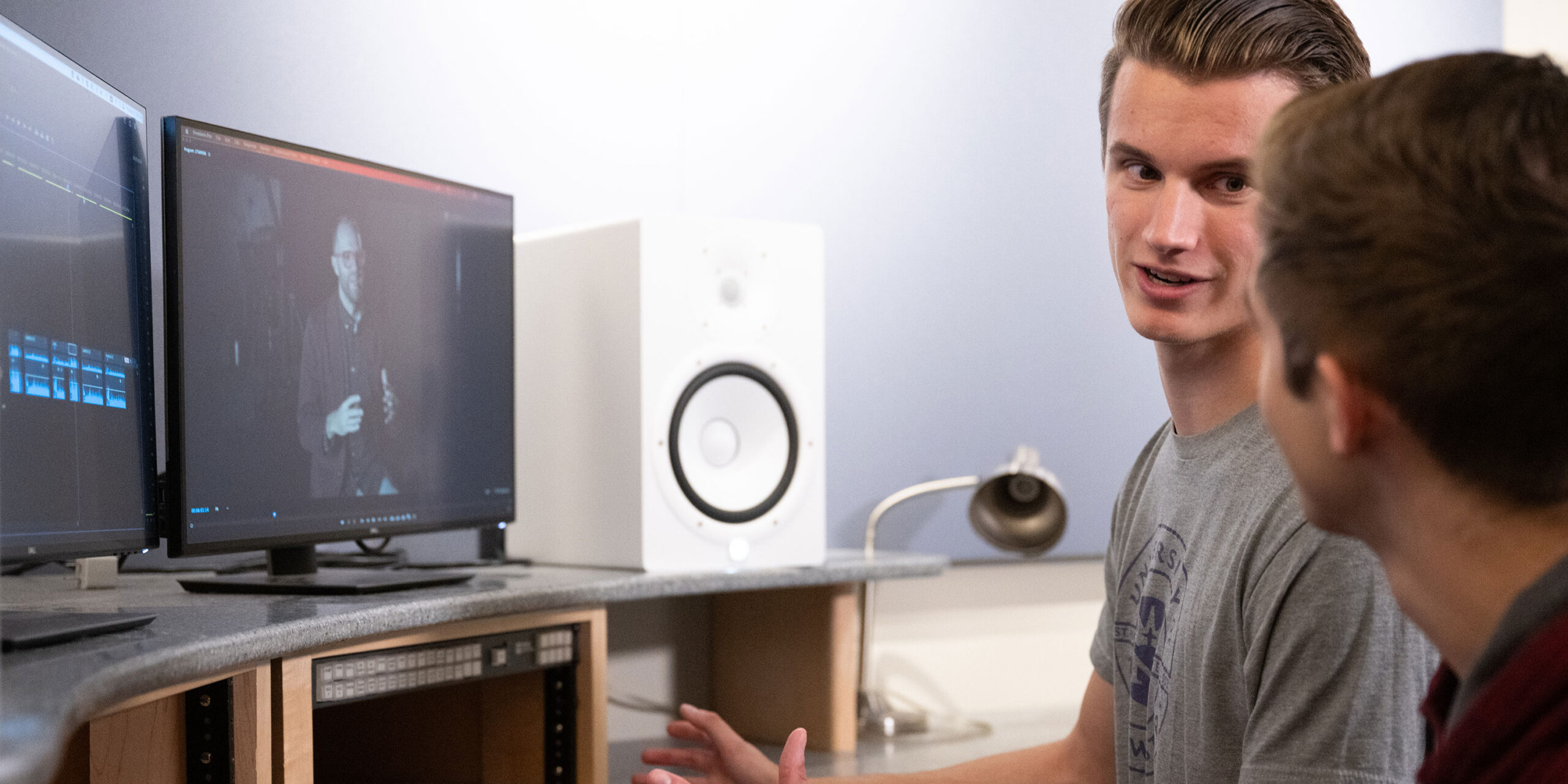 Two male students talking while editing a video.
