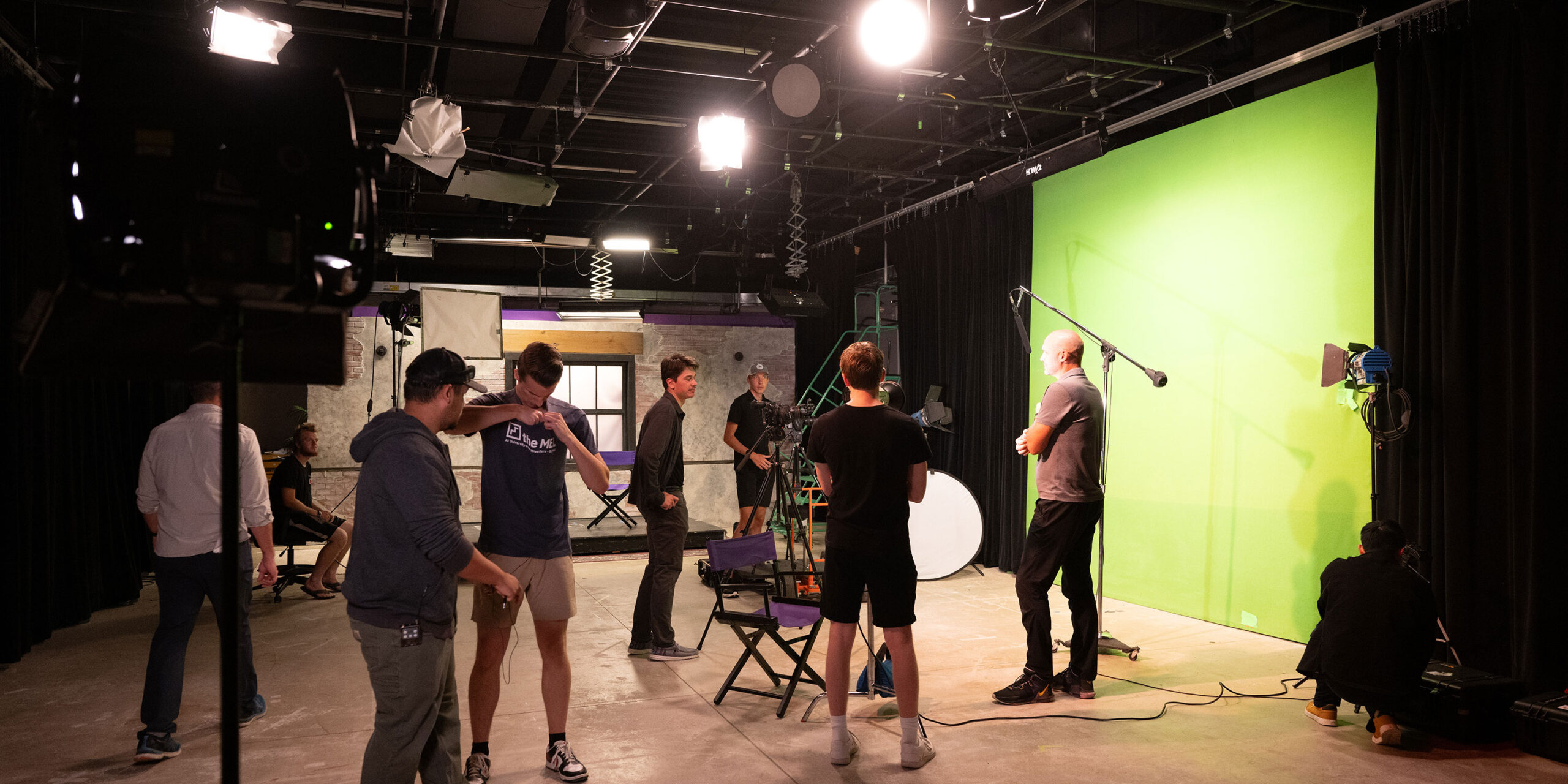 Film students in the studio preparing for a video shoot. Lights, cameras, and a green screen are ready for action.